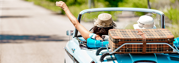 2 adults driving a convertible