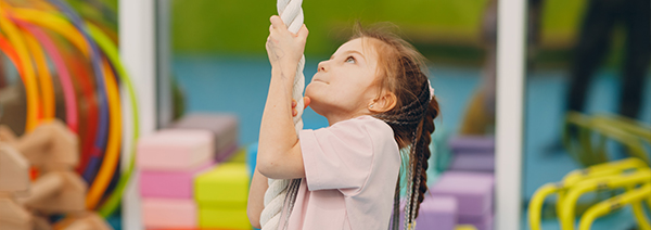 Kids doing exercises climbing tightrope in gym